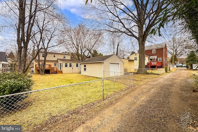 view of front of house with a detached garage, dirt driveway, fence, a front yard, and an outbuilding