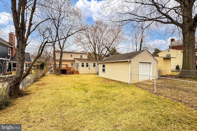 back of house with an outbuilding, a lawn, a detached garage, and fence