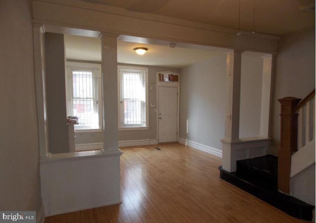 entrance foyer with decorative columns and light hardwood / wood-style flooring