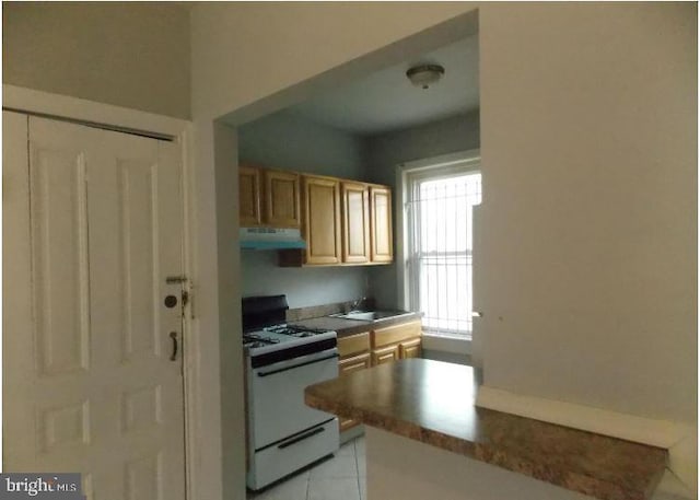 kitchen featuring light tile patterned flooring, sink, and white gas stove