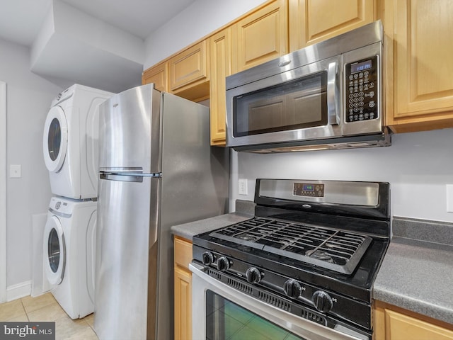 kitchen with stacked washer and dryer, appliances with stainless steel finishes, light tile patterned floors, and light brown cabinetry