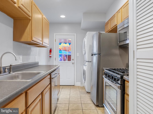 kitchen with appliances with stainless steel finishes, sink, stacked washer and clothes dryer, light tile patterned floors, and light brown cabinets