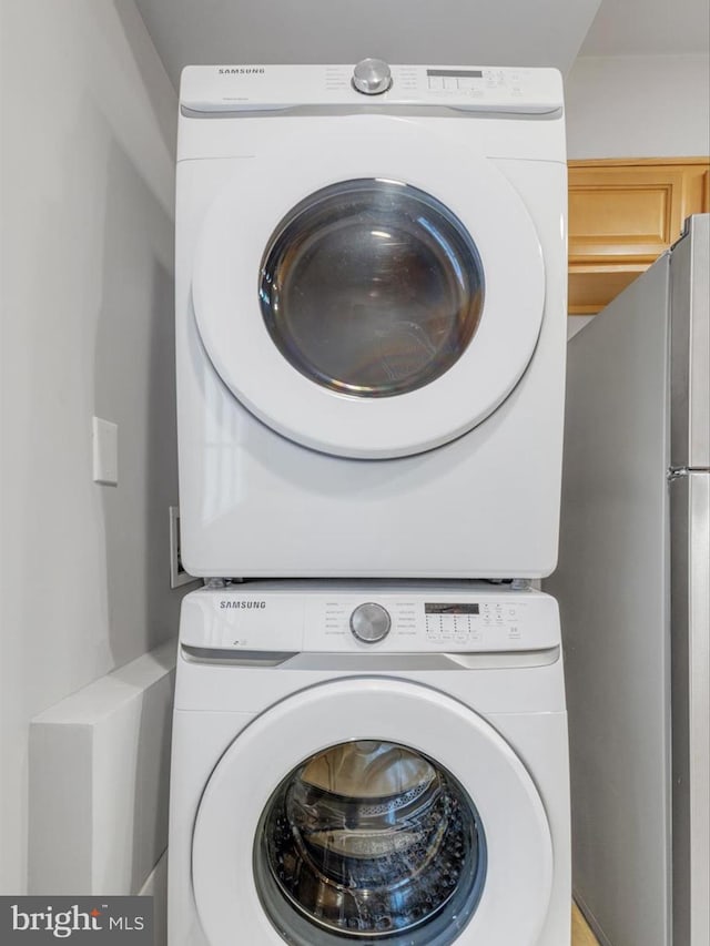 clothes washing area featuring stacked washer and clothes dryer