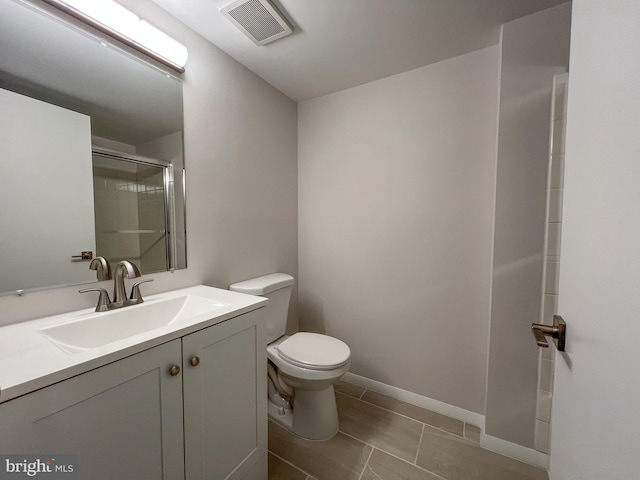 bathroom featuring vanity, a shower with shower door, tile patterned floors, and toilet