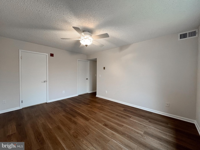 empty room with ceiling fan, dark hardwood / wood-style floors, and a textured ceiling