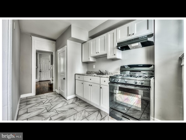 kitchen with light stone counters, sink, black gas range, and white cabinets