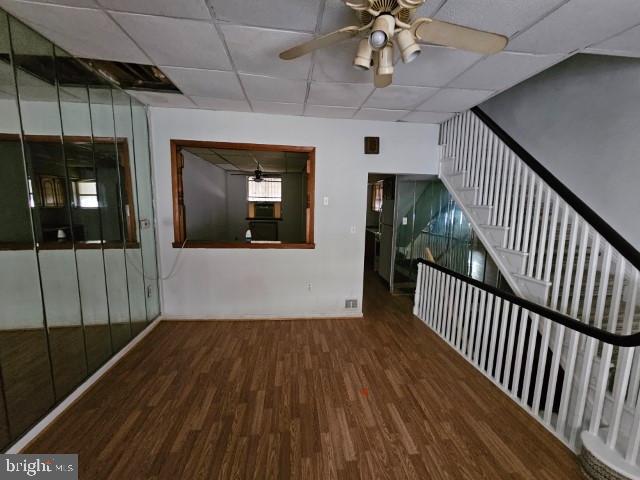 empty room featuring a drop ceiling, dark wood-type flooring, and ceiling fan