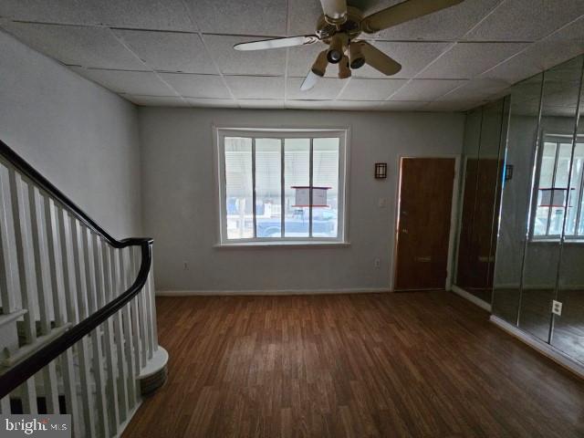 spare room with a paneled ceiling, plenty of natural light, and dark hardwood / wood-style floors