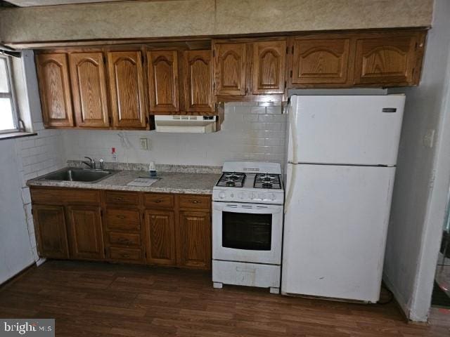 kitchen featuring white appliances, dark hardwood / wood-style floors, sink, and backsplash