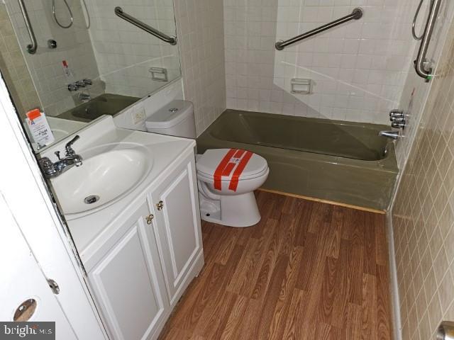 full bathroom featuring hardwood / wood-style flooring, vanity, toilet, and tiled shower / bath combo