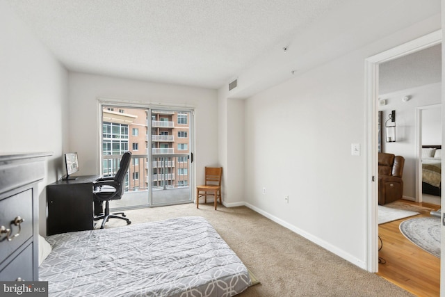 bedroom featuring light colored carpet, a textured ceiling, and access to outside