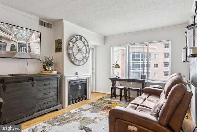 living room with ornamental molding, a textured ceiling, and light hardwood / wood-style floors