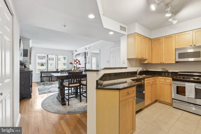 kitchen with sink, dishwasher, dark stone countertops, stainless steel electric range oven, and kitchen peninsula