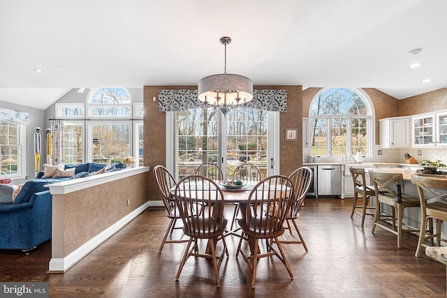 dining room featuring dark wood-style floors, lofted ceiling, a notable chandelier, and baseboards