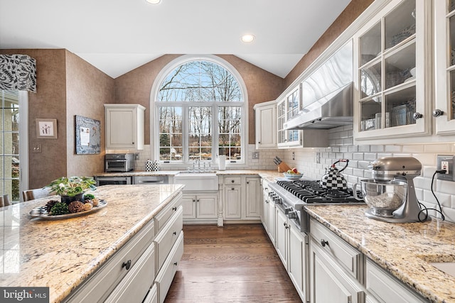 kitchen featuring lofted ceiling, stainless steel gas stovetop, dark wood-type flooring, a sink, and wall chimney range hood