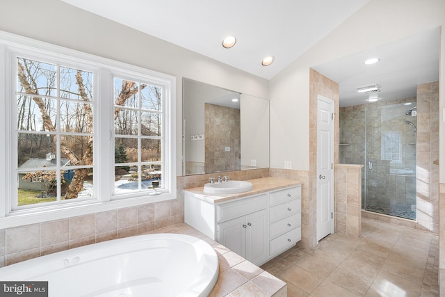 full bathroom featuring a stall shower, a healthy amount of sunlight, a garden tub, and vanity