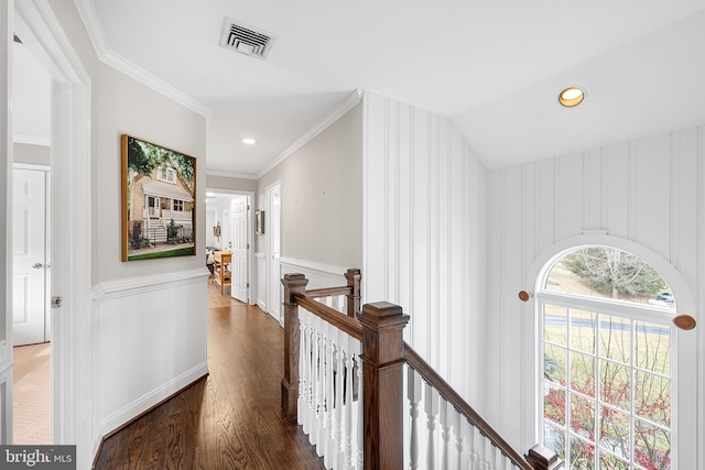 hall featuring a wainscoted wall, wood finished floors, an upstairs landing, visible vents, and ornamental molding