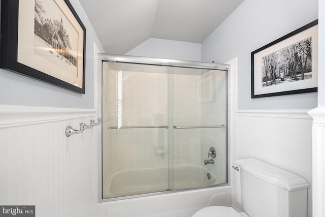 bathroom with enclosed tub / shower combo, wainscoting, vaulted ceiling, and toilet