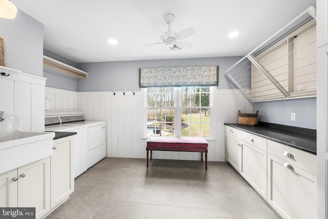 clothes washing area with a wainscoted wall, cabinet space, a ceiling fan, a sink, and separate washer and dryer