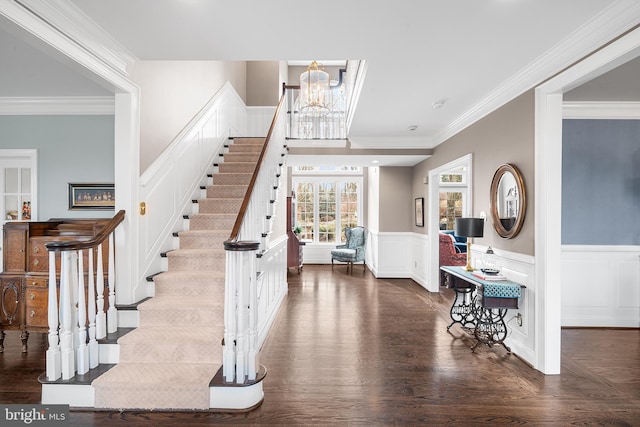 entrance foyer with a wainscoted wall, stairway, an inviting chandelier, ornamental molding, and wood finished floors