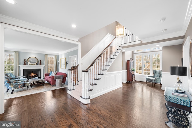 foyer entrance with dark wood-style floors, wainscoting, plenty of natural light, and stairway