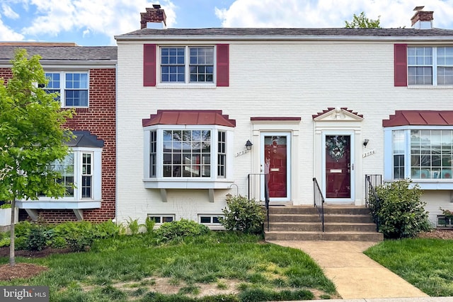 view of property featuring brick siding and a chimney