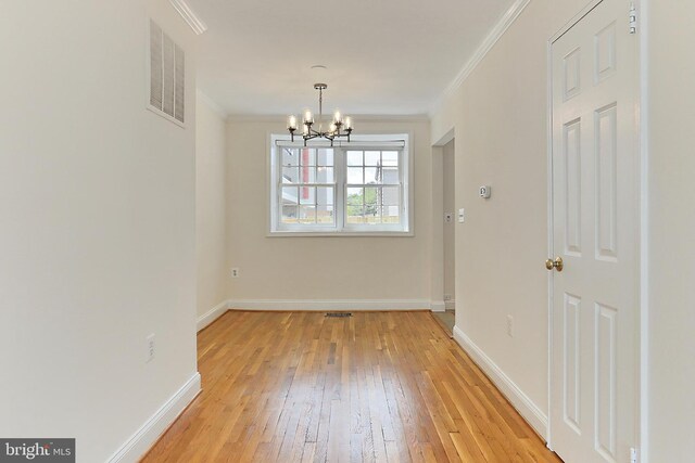 unfurnished dining area with visible vents, ornamental molding, baseboards, light wood finished floors, and a notable chandelier