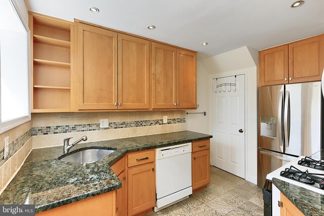 kitchen with white dishwasher, open shelves, gas stove, a sink, and stainless steel fridge