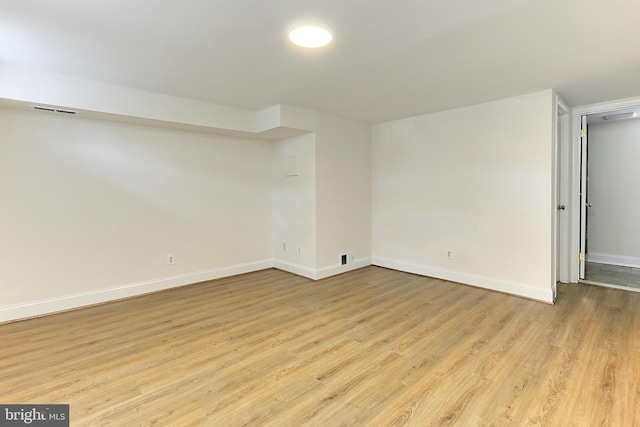 empty room with baseboards, light wood-type flooring, and visible vents