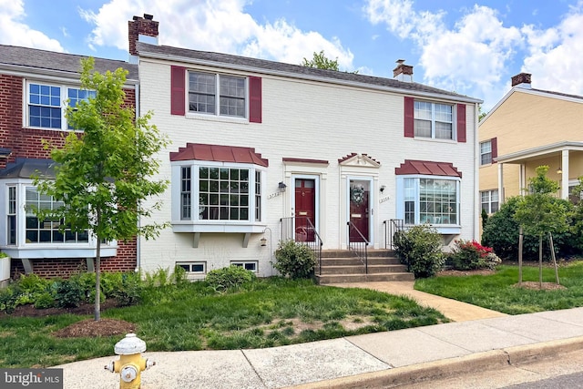 view of front of house featuring a chimney and brick siding