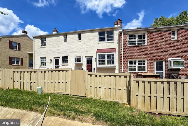 rear view of property with fence, a chimney, and brick siding