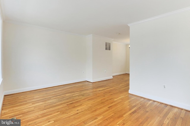 empty room with visible vents, ornamental molding, light wood-style flooring, and baseboards
