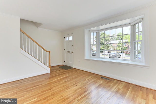 entrance foyer with crown molding, baseboards, hardwood / wood-style flooring, and visible vents