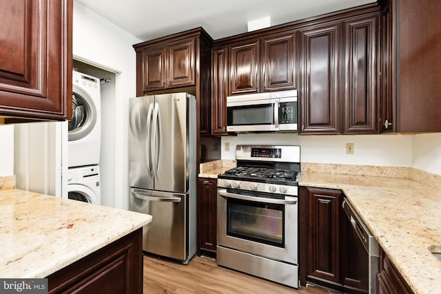 kitchen with stacked washer and dryer, light hardwood / wood-style floors, stainless steel appliances, light stone countertops, and dark brown cabinets