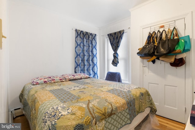 bedroom featuring crown molding, a baseboard radiator, and hardwood / wood-style floors