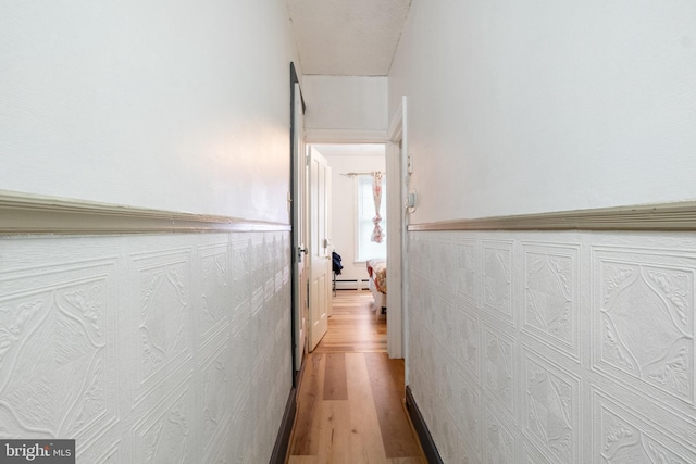 corridor featuring baseboard heating and light hardwood / wood-style floors