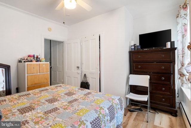 bedroom featuring crown molding, light hardwood / wood-style flooring, ceiling fan, and baseboard heating