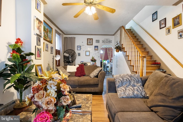 living room with hardwood / wood-style flooring, ornamental molding, and ceiling fan