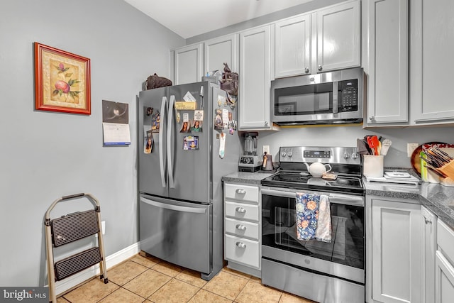 kitchen featuring stainless steel appliances, white cabinetry, heating unit, and light tile patterned flooring