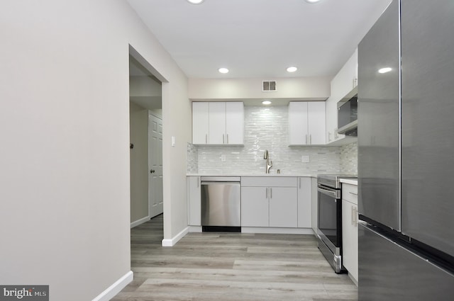 kitchen with tasteful backsplash, sink, white cabinets, and appliances with stainless steel finishes