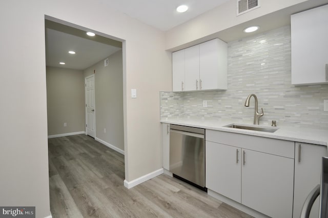 kitchen with dishwasher, sink, white cabinets, and decorative backsplash