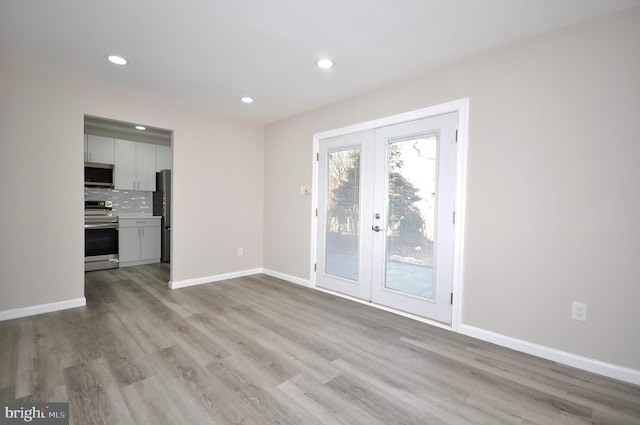 spare room featuring light hardwood / wood-style flooring and french doors