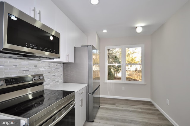 kitchen featuring white cabinetry, decorative backsplash, light hardwood / wood-style floors, and appliances with stainless steel finishes