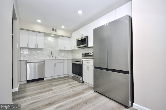 kitchen with sink, light hardwood / wood-style flooring, white cabinetry, stainless steel appliances, and tasteful backsplash