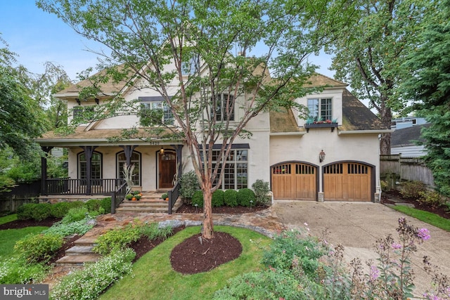 view of front facade with driveway, a garage, fence, a porch, and stucco siding