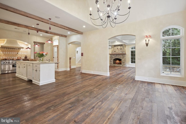 unfurnished living room with arched walkways, dark wood-type flooring, a fireplace, baseboards, and beam ceiling