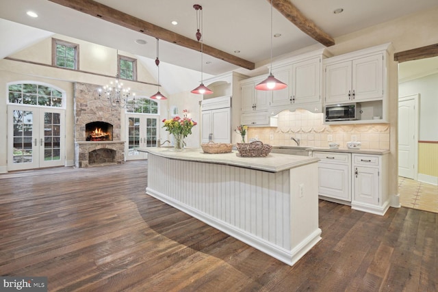 kitchen with a sink, open floor plan, light countertops, french doors, and stainless steel microwave