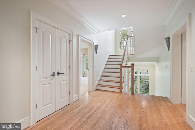 entryway featuring ornamental molding, a healthy amount of sunlight, stairs, and wood finished floors