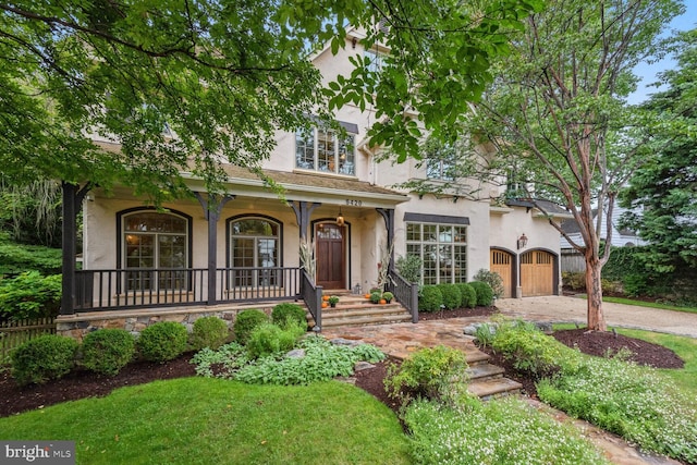 view of front of property featuring driveway, covered porch, a gate, and stucco siding