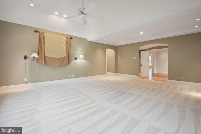 spare room featuring baseboards, arched walkways, and light colored carpet